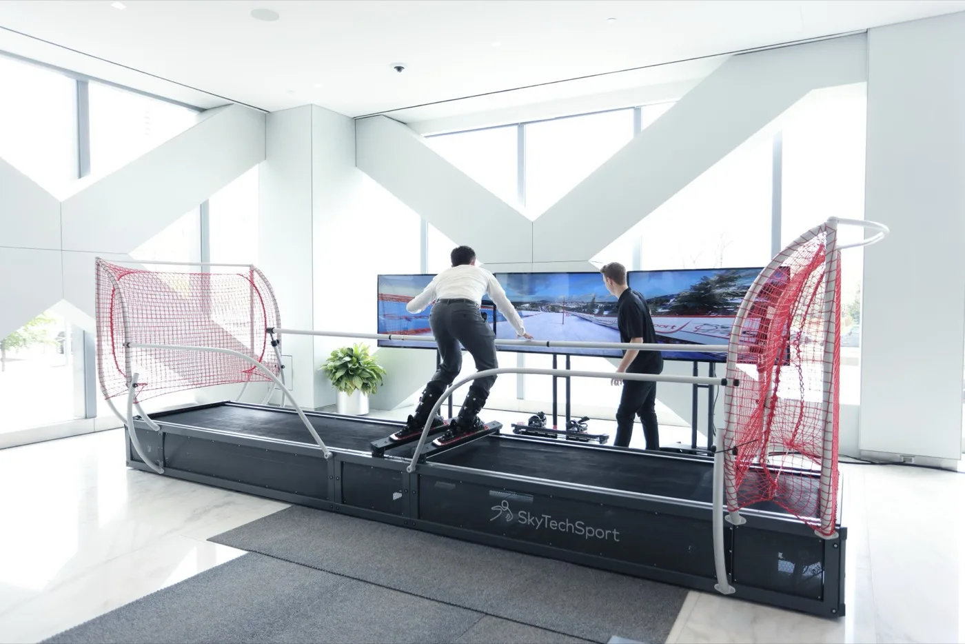 Guests skiing a SkyTechSport simulator in a bright public atrium