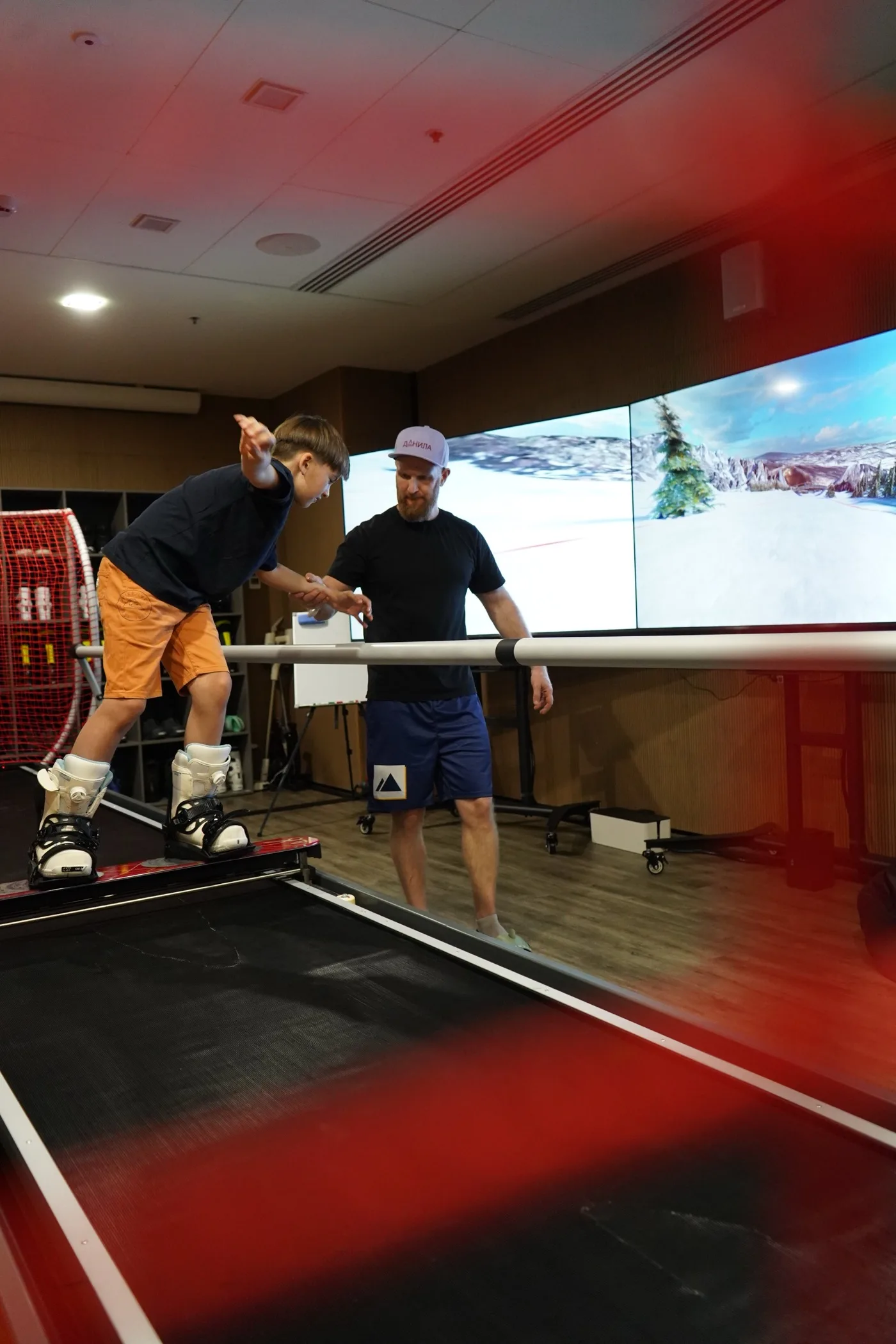 An instructor coaching a young guest on a SkyTechSport ski simulator