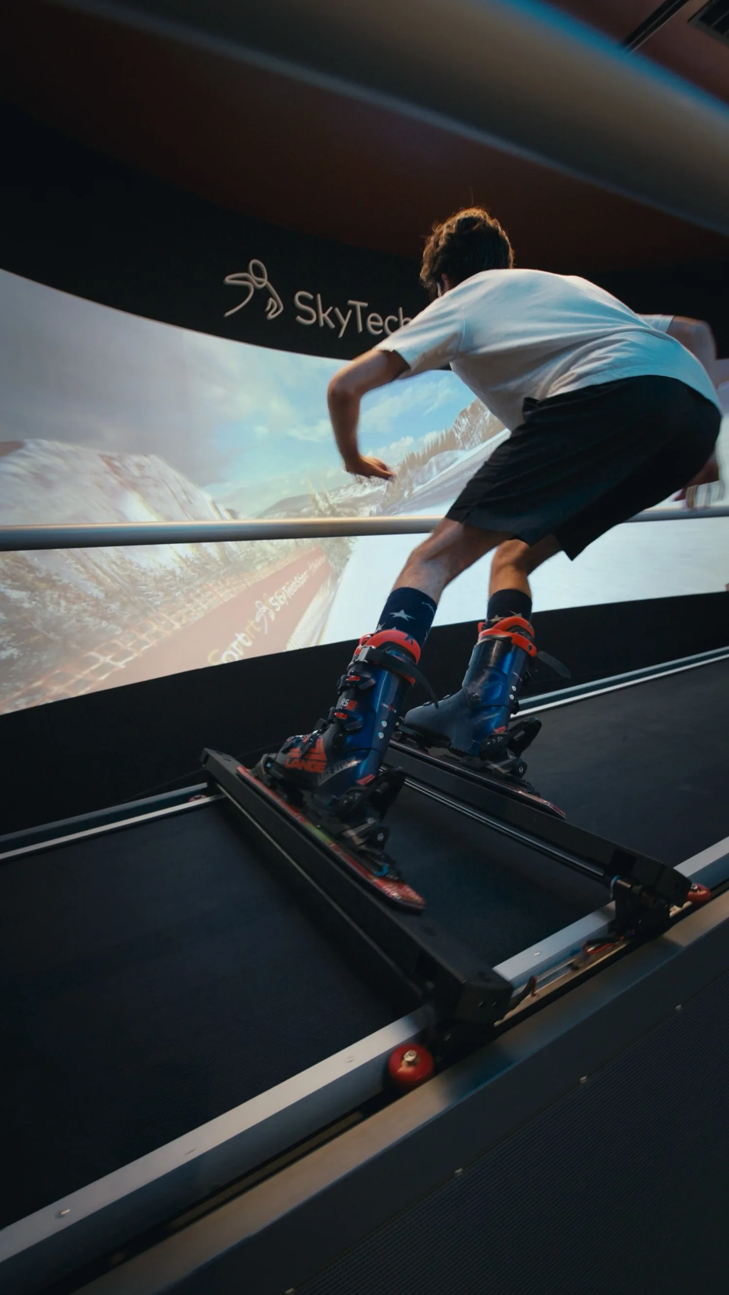 A skier carving on a SkyTechSport simulator in front of a wraparound projection screen