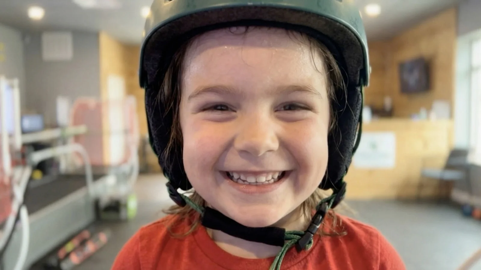A smiling child in a helmet after a run on the SkyTechSport ski simulator